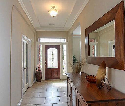 The entry features a wood and leaded-glass front door, 18" tile floors and a trey ceiling.