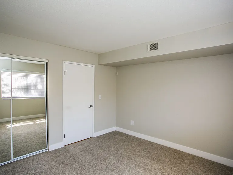 Bedroom with large baseboards, two-tone paint, and mirrored sliding closet doors.