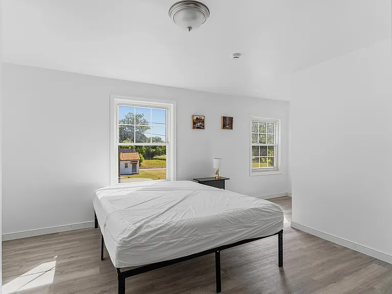Spacious bedroom with two windows for natural light, neutral walls, and durable flooringideal for easy, comfortable living.