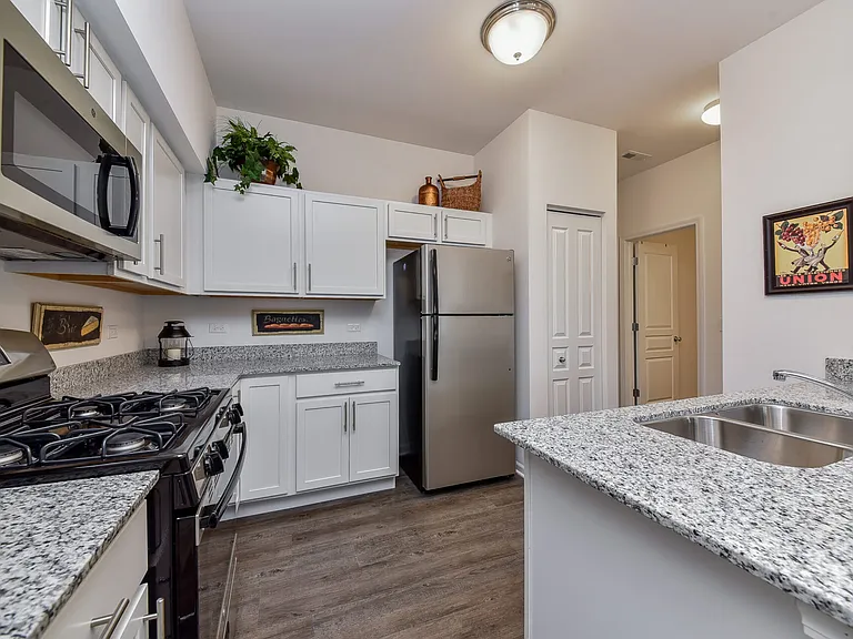 Modern kitchen with white cabinets, stainless steel appliances, and granite counter tops.