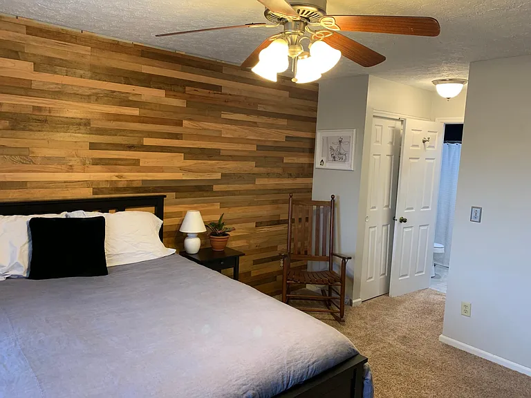 Spacious master bedroom with a gorgeous wood accent wall and ensuite bathroom.