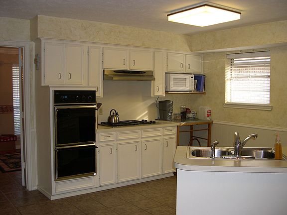 Kitchen has double oven, gas stove, and deep stainless steel sink.