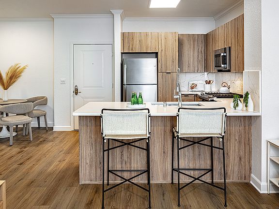 Gourmet kitchen and dining area with stainless steel appliances, quartz countertops and wood-style flooring.