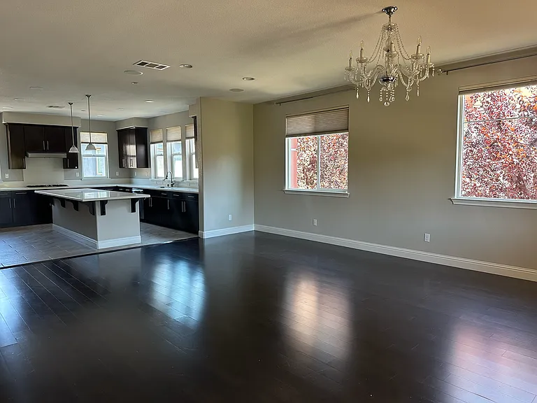 Expansive living room with rich hardwood floors, abundant natural light, and a open layout ideal for entertaining.