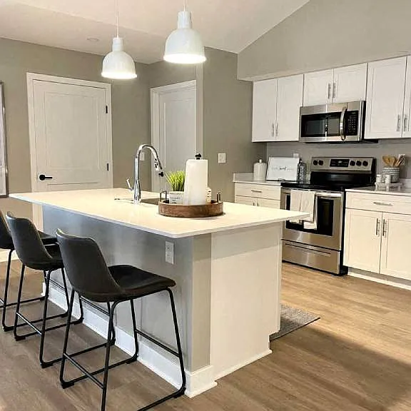 Interior of Champion Reserve Townhome with view of well equipped kitchen with stainless steel appliances, quartz countertops, and breakfast bar/kitchen island.