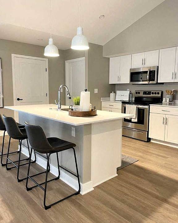 Interior of Champion Reserve Townhome with view of well equipped kitchen with stainless steel appliances, quartz countertops, and breakfast bar/kitchen island.