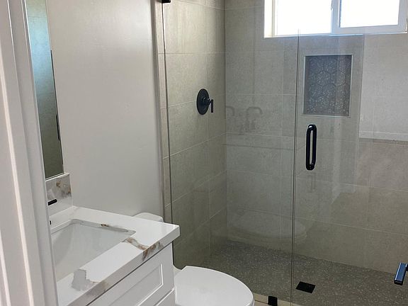 Typical bathroom with glass shower door surround, full height tile showers, quartz countertops and modern black fixtures.