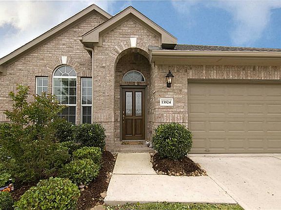A landscaped lined walkway leads up to the beautiful leaded glass door.