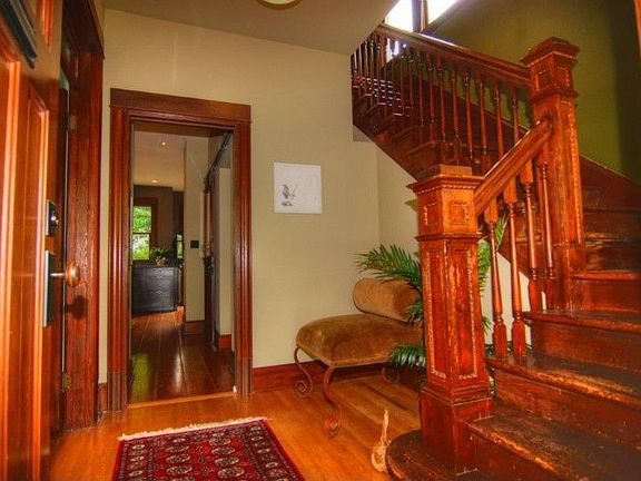Lovely foyer with original wood banister. French doors lead to living room (left), kitchen (straight