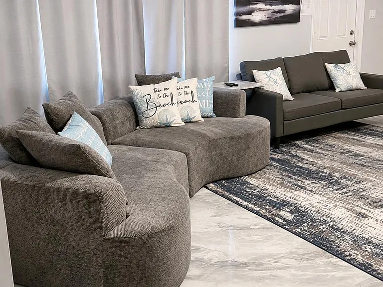 Comfortable living area with two sofas, large tile flooring, and window coverings for privacyideal for relaxing or entertain