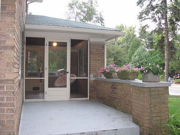 Enter into an outdoor patio and screened porch w/original b-board ceiling.