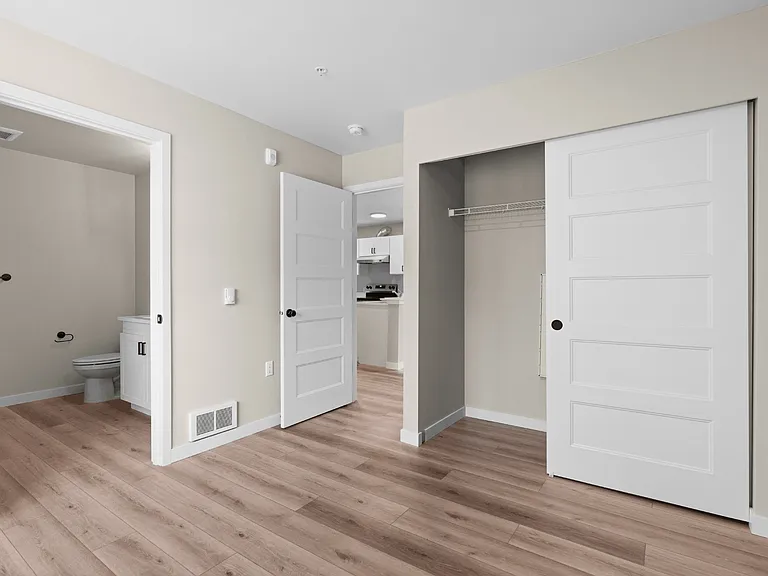 Apartment bedroom with luxury vinyl plank flooring, sliding closet doors, and an attached bathroom. Apartment bedroom with luxury vinyl plank flooring, sliding closet doors, and an attached bathroom.