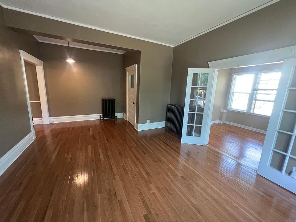 Large living room with 10 foot ceilings, oak hardwood floors, crown moldings, tall baseboards, and decorative fireplace