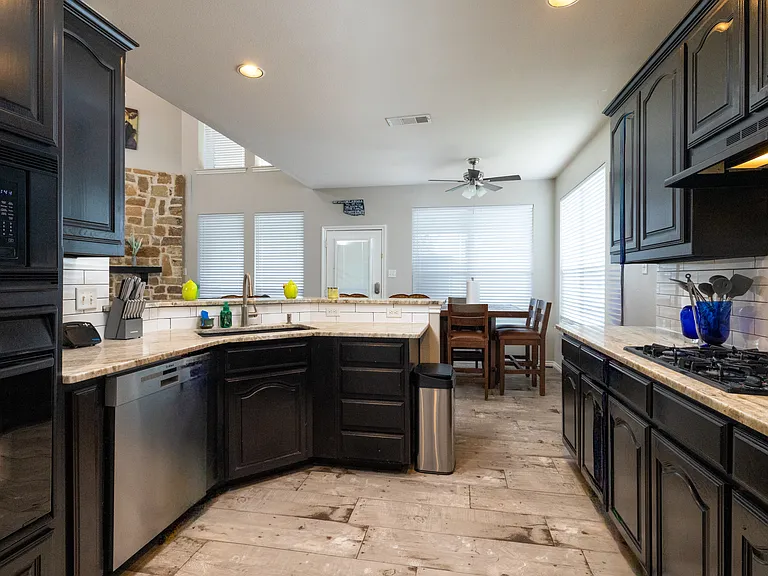 Bright kitchen with black cabinets, stainless appliances, and a curved breakfast bar with seating. Perfect for cooking, gathering, and enjoying meals together.