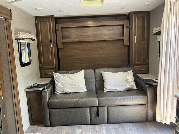 Two-person sofa with flip-up leg rests. Queen Murphy bed is located behind sofa and pulls down over it.