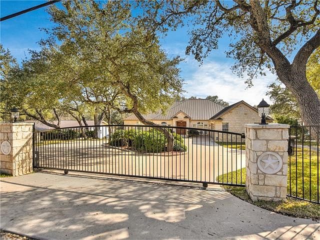 An elegant iron gate greets you at the entrance of this special waterfront property on Lake Travis.