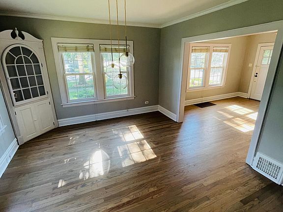 New brass light fixture adds a modern vibe to the charm of the dining room with original built in cabinets for ample storage.
