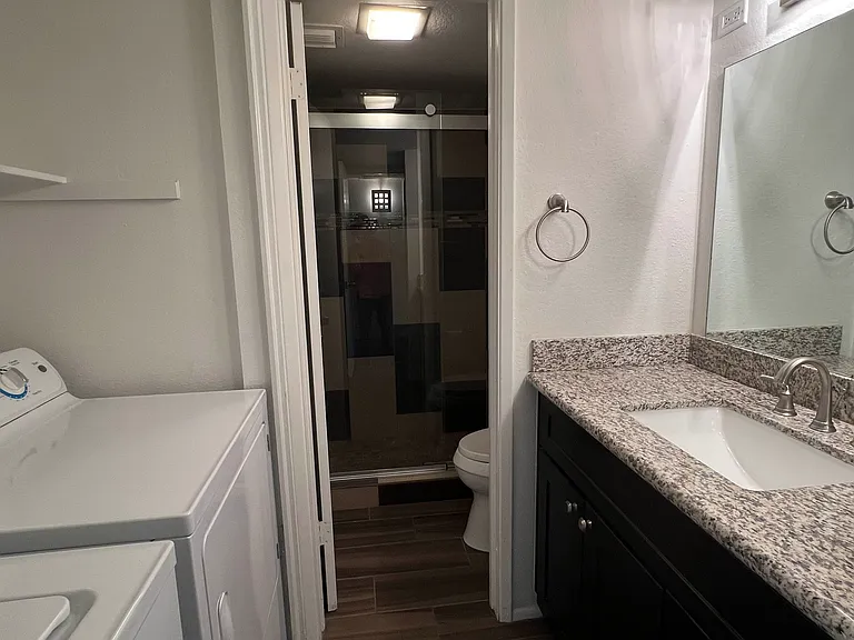 Chick and Stylish | The first bathroom with a modern design shower with cool sliding doors, and toilet with bidet, separate from your granite-top sink. Your in-unit new LG washer and dryer tucked conveniently in the niche across your sink and cabinets.