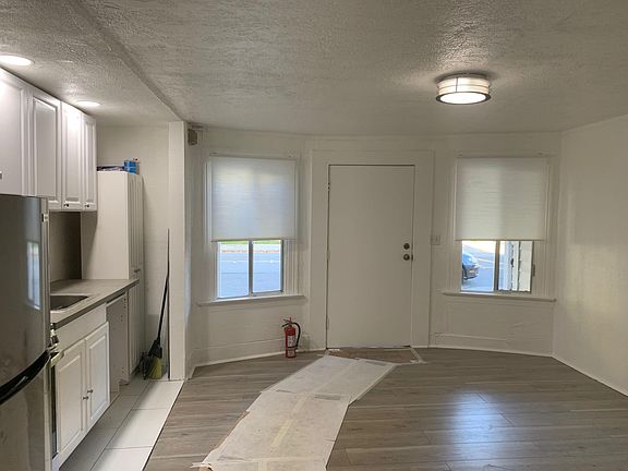 View of kitchen+living room with new floor and pull down blinds