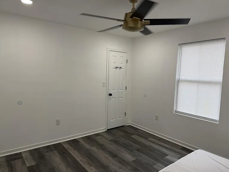 Private bedroom with durable wood-look flooring, ceiling fan, and a window with blinds for light and privacy.