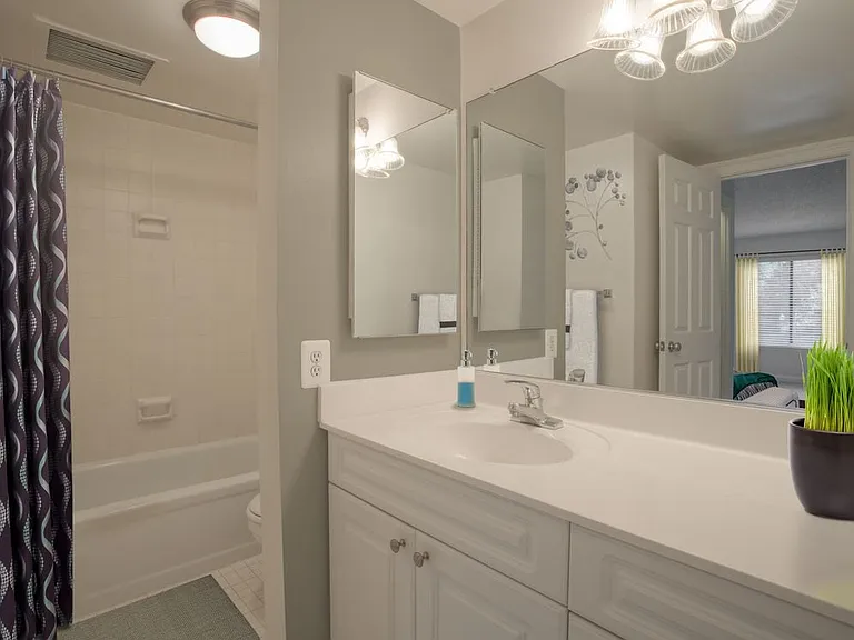Bathroom with white countertops, white cabinetry and tiled bathtub