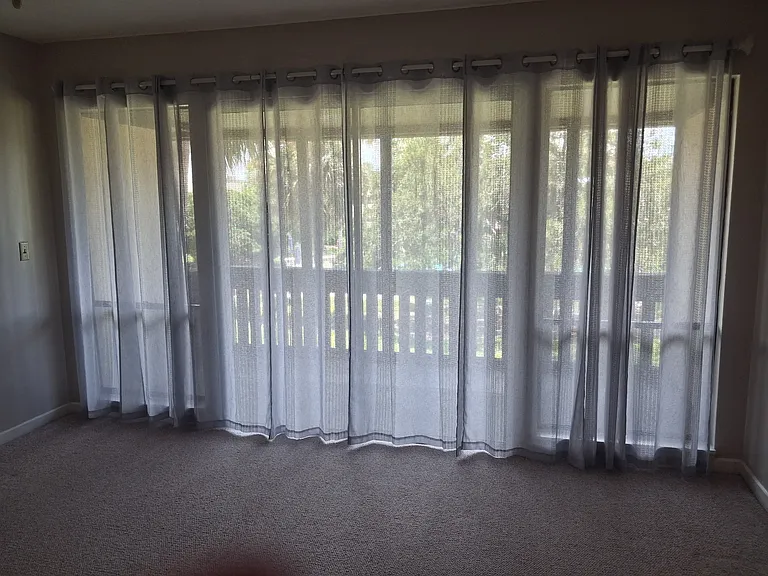 Master Bedroom with view of large screened in porch which can easily accommodate chairs and small table. Overlooks pool area. Presently has light blue full linen curtains.