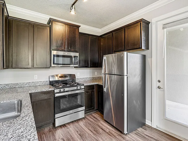 Modern kitchen with sleek stainless steel appliances, dark wood cabinets, and elegant granite countertops.