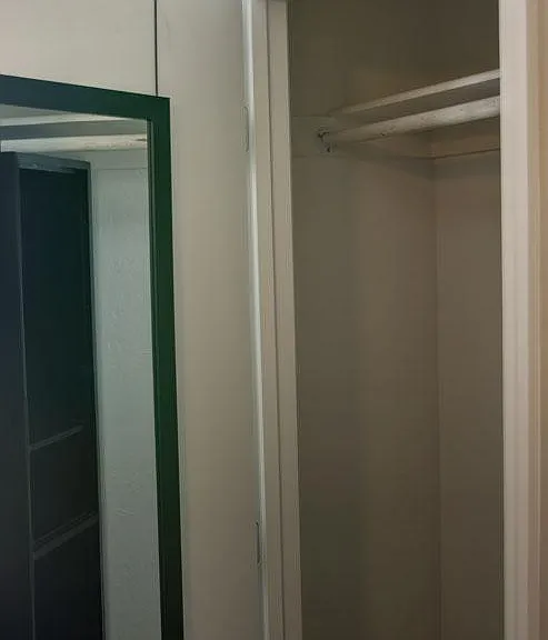 Reach-in closet with hanging rod and upper shelf for convenient everyday storage.