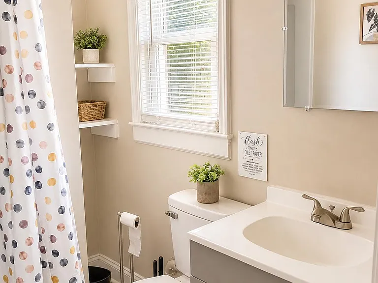 Full bathroom with tub/shower, single-sink vanity, and window for ventilation plus built-in shelving for toiletries.