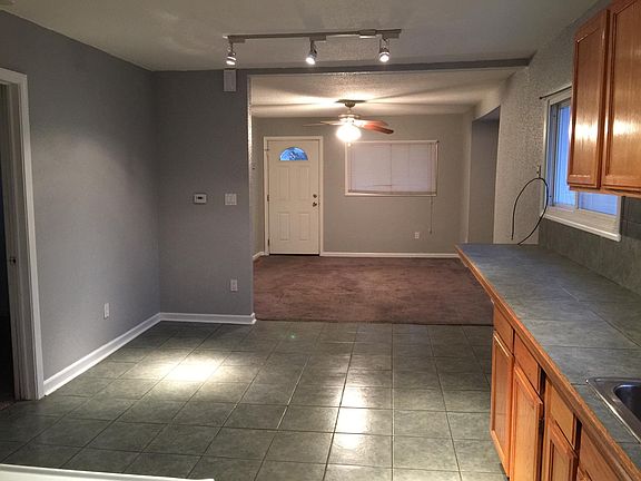 Open floor plan shows kitchen/dining area with front room. Door to left is a bedroom