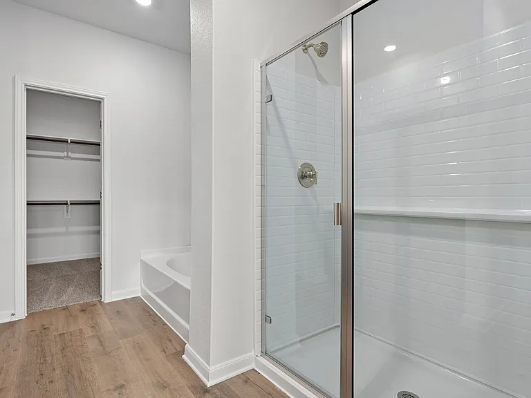 The master bathroom has a large, glass walk-in shower and a garden tub.
