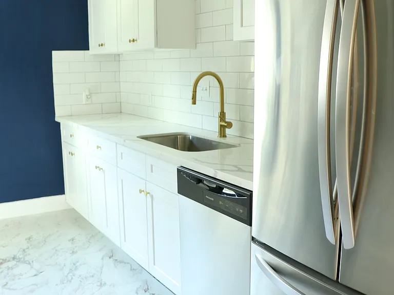 Quartz countertops, deep sink, and gold hardware for a stylish finish.