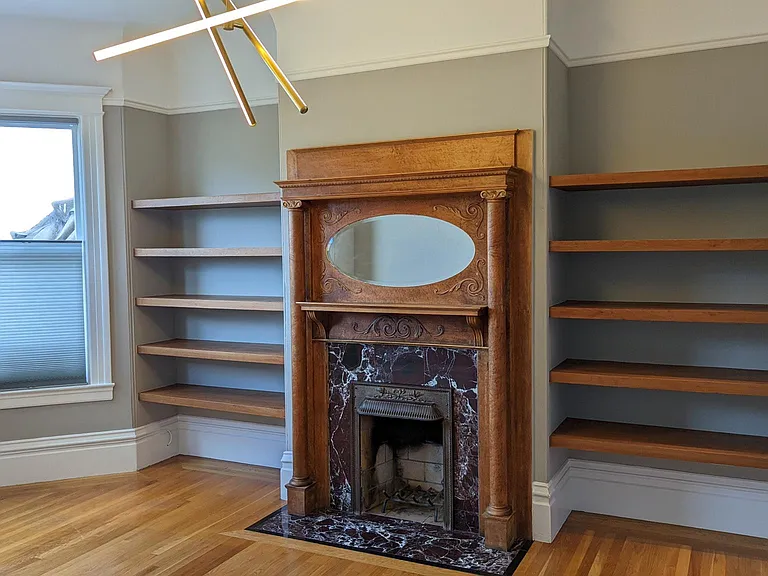 Another view of the office with decorative fireplace and custom shelves