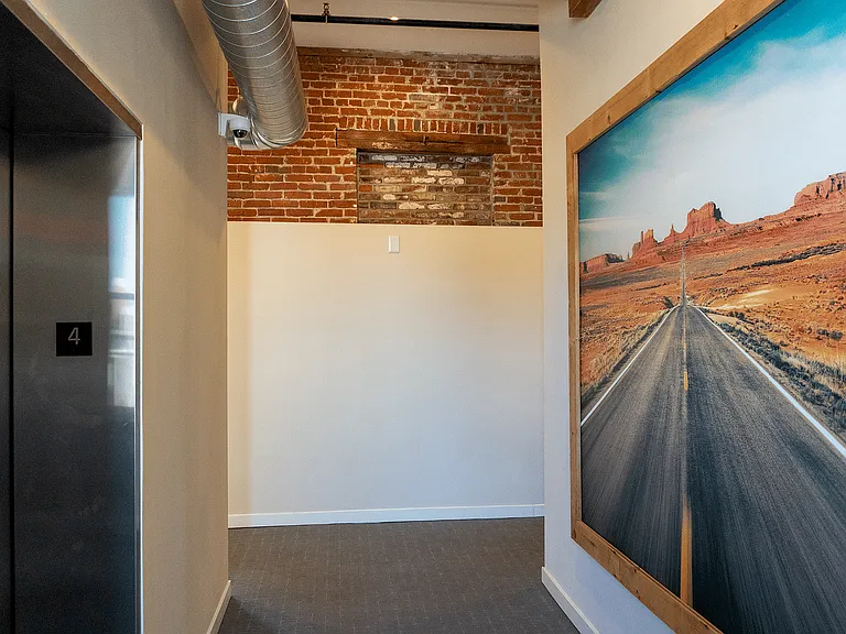 Step into elegance with this chic urban hallway featuring a blend of rustic charm and modern art.