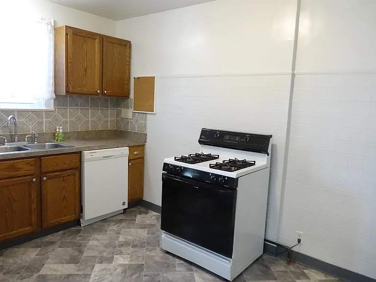 Kitchen with gas range and oven, dishwasher, disposall, and fresh vinyl floor.