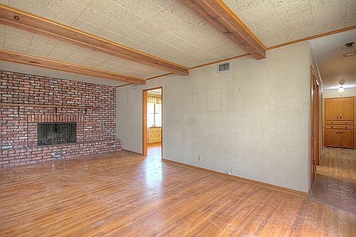 Spacious Family Room with hardwood floors, crown moulding and rustic ceiling beams. Entryway offers 