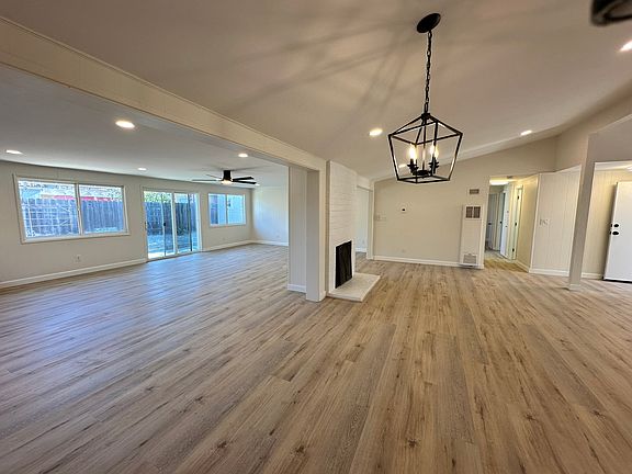 Charming family room with a cozy wood fireplace flows into a dining area with an elegant chandelier, plus a spacious great room featuring a separate gas fireplace for cozy nights or formal gatherings.