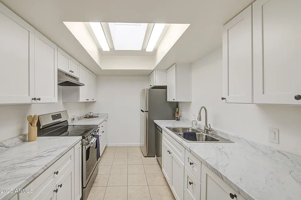 Kitchen with sky light, new lighting, new stainless steal appliances, new counter tops, new cabinets.