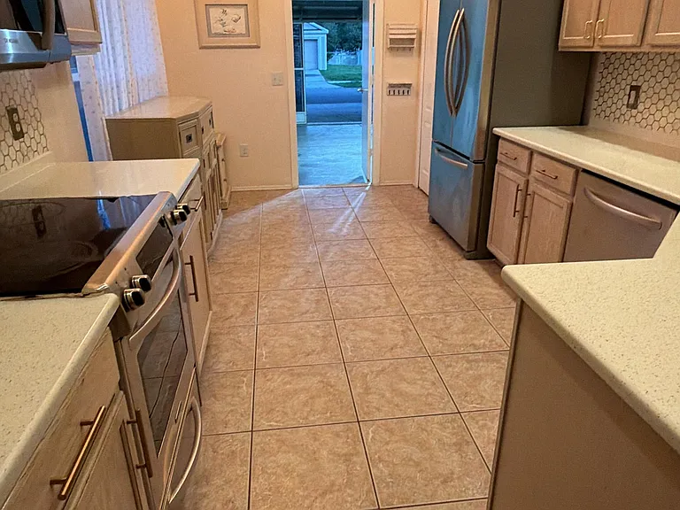 Kitchen has tall ceilings, large window, stainless steel appliances and granite countertops.