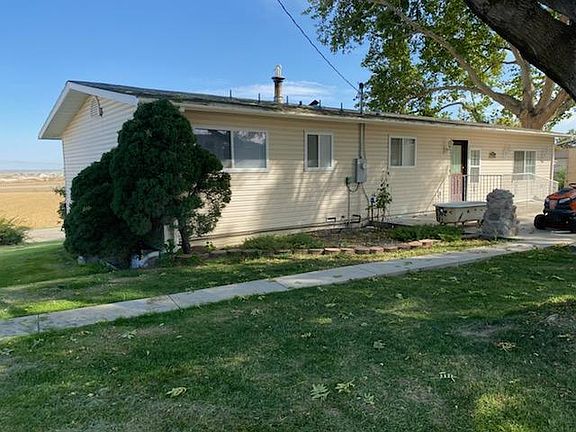 View of house rear with valley vista in background to the left. A wheelchair ramp services the back door of this upper level duplex. Patio and driveway are to the right and not visible. The back driveway serves the upper level duplex. Entrance to the