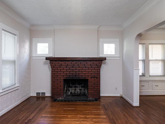 Charming Livingroom with original oak floors, woodwork and brick fireplace.