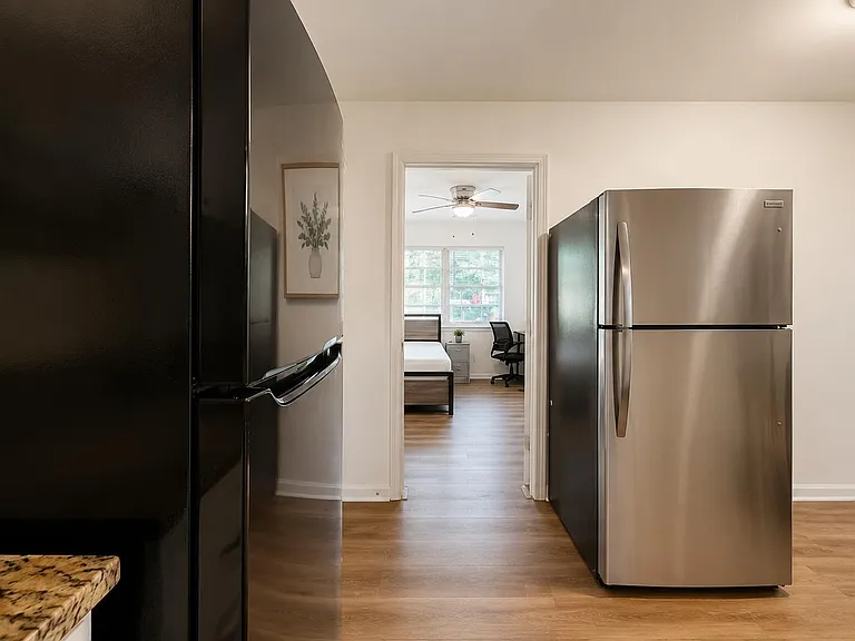Spacious kitchen area with full-size stainless-steel refrigerator and open layout connecting to adjacent rooms.