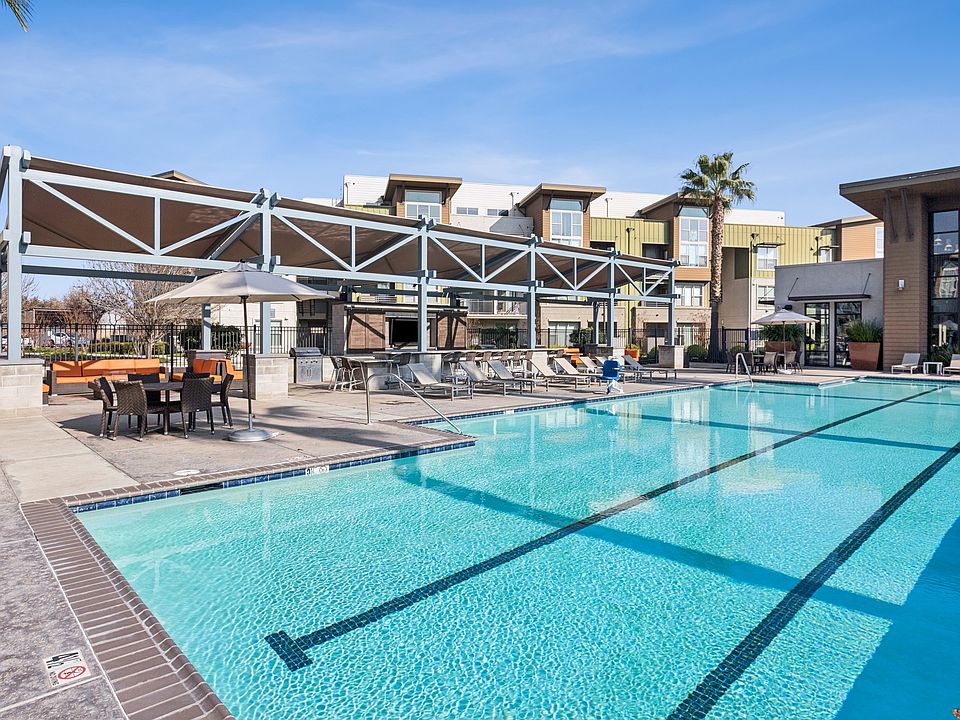 Aspire Apartments Tracy California Luxury Living A large swimming pool in front of a building with palm trees.