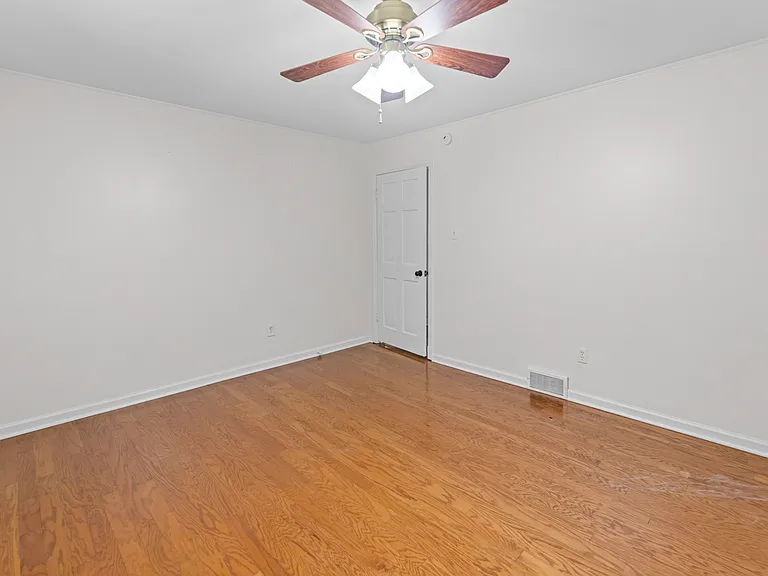Light and airy bedroom with hardwood floors and ceiling fan _ a clean canvas ready for your personal touch.