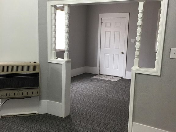 Dining room has gas wall heater and window AC. View into li