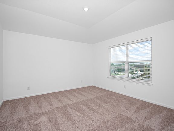Master bedroom with a vaulted ceiling, recessed lighting, and large windows.