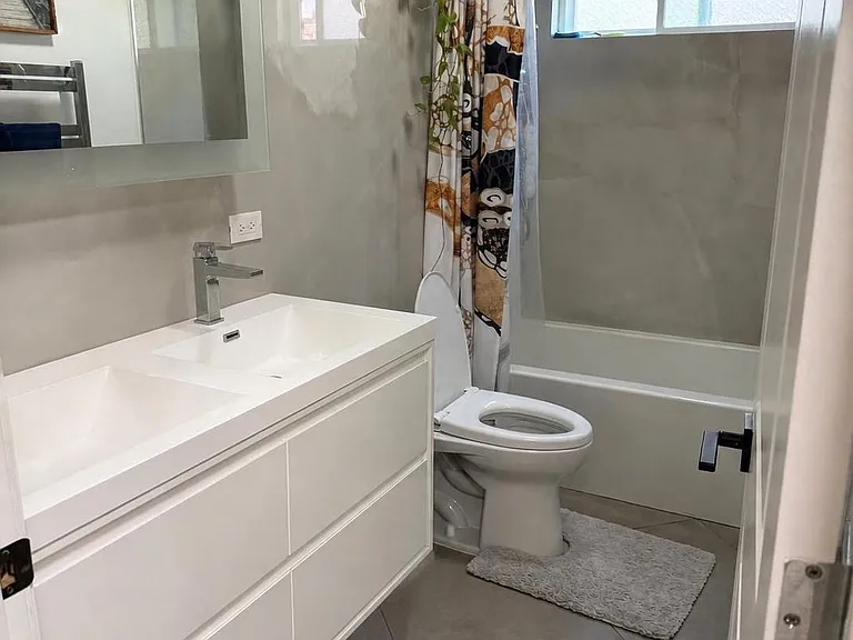 Main bathroom with Grohe shower system, solar tube, high end porcelain slab walls, double sink, towel warmer.