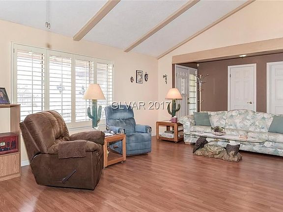 Formal living room has laminate flooring, fireplace and shutters on the window.