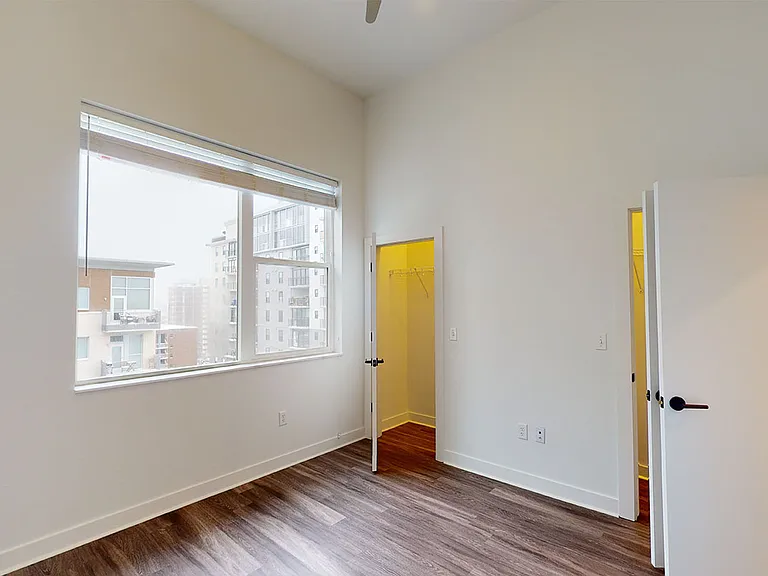 Spacious apartment bedroom with large closet and wood-style flooring.