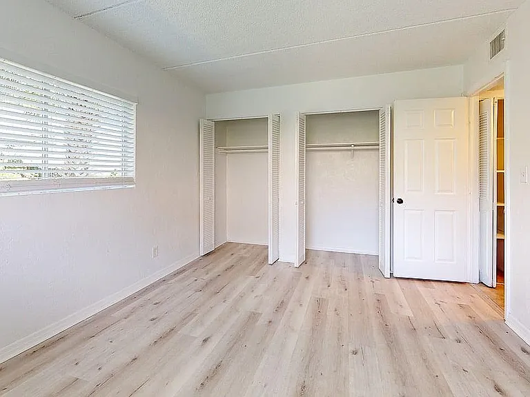 Bright and airy bedroom with large windows, spacious closets, and elegant flooring.